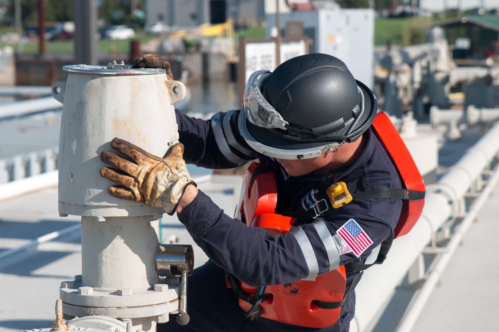 A man in uniform working a tankerman trainee job in the sun.