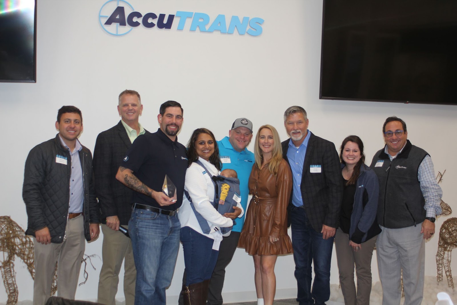 Members of the AccuTRANS family smiling and posing with a winner of the Tenure Award at a Christmas party.